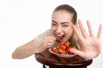 girl eagerly eating strawberries on white background.