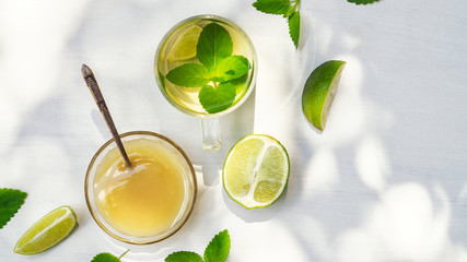 Lime tea with mint in a glass cup and honey on a white background