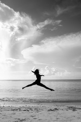 SILHOUETTE OF WOMAN LEAPING THROUGH THE AIR AT A BEACH