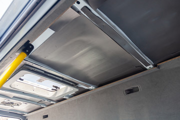 Tuning the car in a van bus body with three layers of noise insulation on the metal roof. Sound and vibration isolation using soft and rubber material with a car breakdown. Auto service undustry.