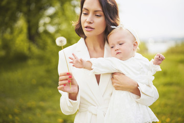 Mother and daughter blowing to dandelion