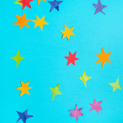 stars cut from colored papers on blue paper