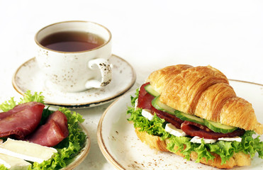 croissant sandwich and tea. breakfast in French. jerky, camembert ch