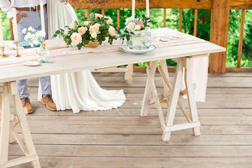 Decorated table for dinner for two person, with plates knife, fork, cheese, wine, wine glasses and flowers in a copper vase.