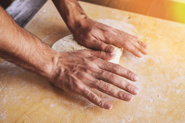 Close-up of men's hands roll out, prepare the basis for pizza