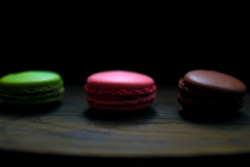 Obraz na płótnie Canvas Multi-colored macaroons on a wooden tray. Pink, yellow and green macaroon.