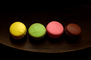 Multi-colored macaroons on a wooden tray. Pink, yellow and green macaroon.