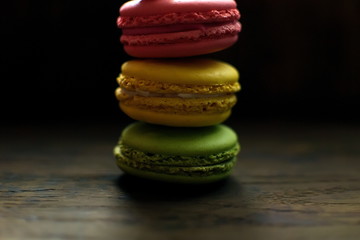 Multi-colored macaroons on a wooden tray. Pink, yellow and green macaroon.