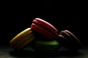 Multi-colored macaroons on a wooden tray. Pink, yellow and green macaroon.