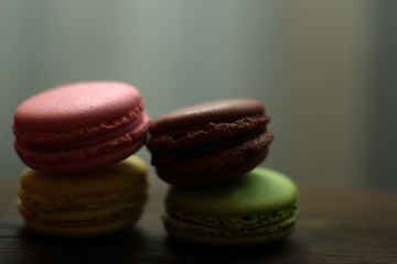 Multi-colored macaroons on a wooden tray. Pink, yellow and green macaroon.