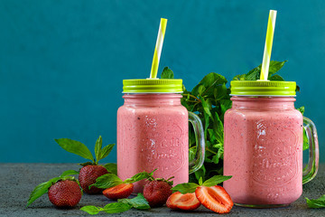 Freshly prepared fruit and milk summer cocktail of ripe berries. Refreshing strawberry mint smoothie with ice cream on wooden background. Soft diet drinks for a healthy lifestyle.