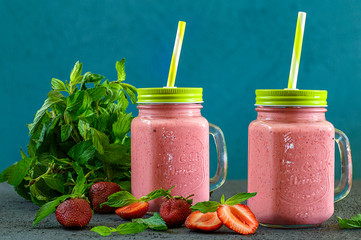 Freshly prepared fruit and milk summer cocktail of ripe berries. Refreshing strawberry mint smoothie with ice cream on wooden background. Soft diet drinks for a healthy lifestyle.