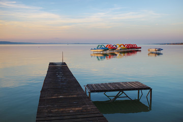 Wooden pier and paddle boats on lake Balaton at sunset, in Hungary