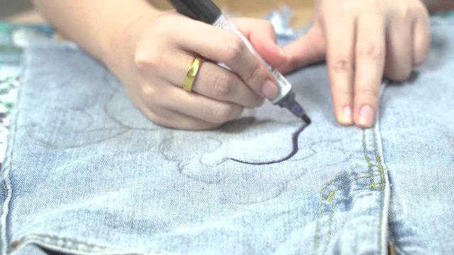 Women hands are creating art pieces, using brushes. Skirt painting