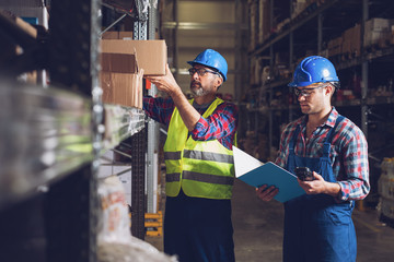 Two warehouse workers filling in document 