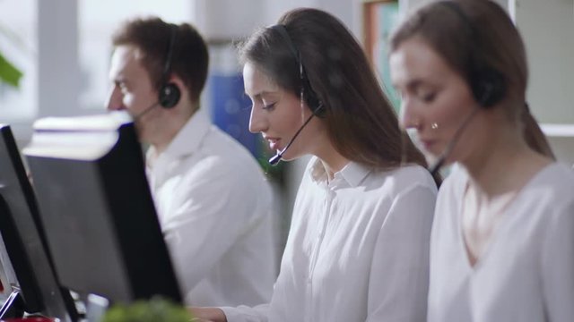Close up young people woman man operator taking calls use computer smile in call center office business worker corporate headset job man service group finance sunshine phone close up slow motion