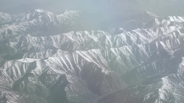 Aerial view of snowy mountains. View from the plane on a mountain folds. The tops of the mountains covered with snow view from the window of the plane. Alborz or Alburz, Elburz or Elborz