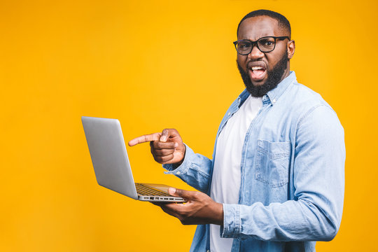 African american ypung man scared a bad news on his laptop, isolated against yellow background.