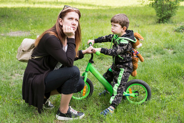 Mom and son are walking together in the park, mother is offended by his son and looking up, and the boy looks at his mother angrily