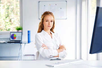 Young businesswoman sitting at office desk in front of computer