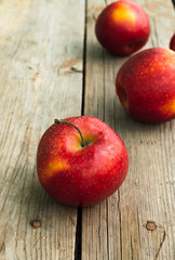 Ripe red apples on a wooden old table. Vertical photo, close-up