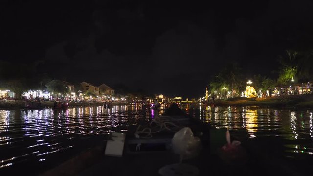 Wooden boat cruising down the river in Hoi An, Vietnam at night