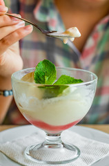 young girl's hand holding a spoon and  eating ice cream in glass at a table in cafe