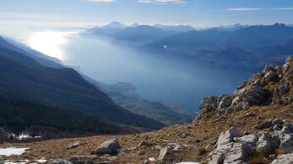 Fototapeta na wymiar View of Lake Garda from the top of Baldo. Beautiful blue water, sky and sharp mountain peaks (Alps and Dolomites)