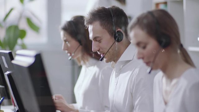 Employee young people woman man operator taking calls use computer smile in call center office business worker corporate headset job man service group finance sunshine phone close up slow motion