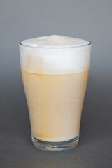 large transparent glass filled with cold summer drink coffee with milk photographed on the isolated gray background picture for the menu