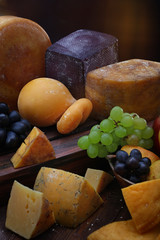 Still-life from firm grades of cheese and fruit on a black background. Side view. The concept of still life or illustration.