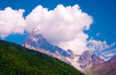 Green and snowy mountains, clouds and glacier