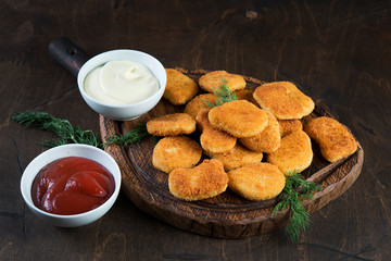 Chicken nuggets with greens and sauce on a wooden Board. Fast food, snack, dinner in European style.