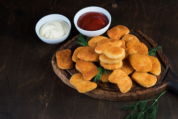 Chicken nuggets with greens and sauce on a wooden Board. Fast food, snack, dinner in European style.