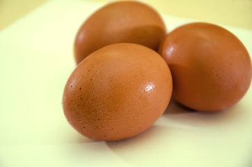 three chicken eggs on a yellow background, close-up