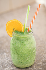 Summer healthy detox drink: blended green smoothie in a city park or garden in the bright midday sun