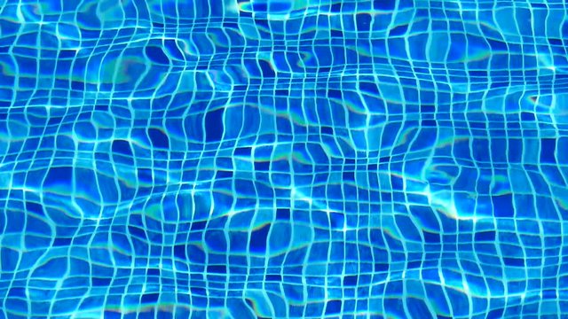 Water texture. The reflection of the rays of the sun in the clear water of the blue pool.