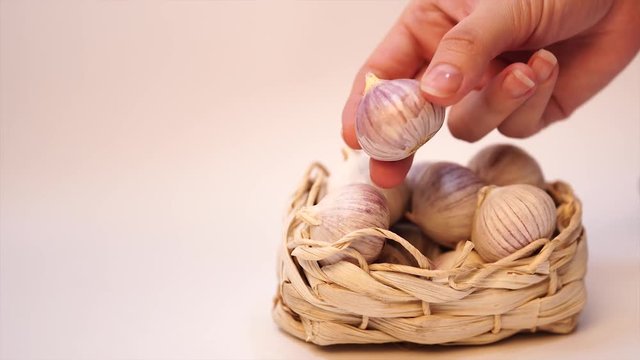 Garlic in a wicker basket, on a white background. Dried French garlic. Red garlic.