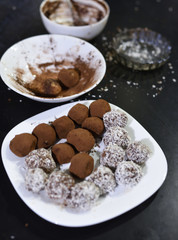 Truffles making on dark background, cocoa powder and coconut