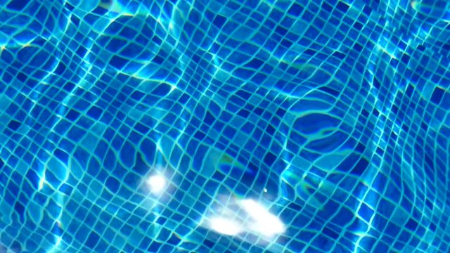 Water texture. The reflection of the rays of the sun in the clear water of the blue pool.