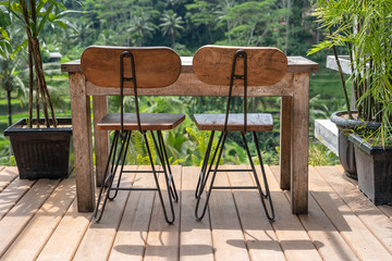 Obraz premium Wooden table and chairs in empty tropical cafe next to rice terraces in island Bali, Indonesia