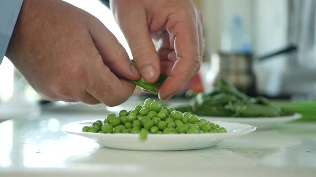 Man Working in the Kitchen Select and Clean Fresh Green Peas for Cooking