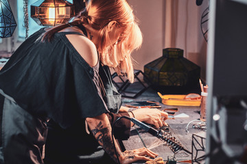 Teacher and student at glass workshop have a lesson about how to do soldering.