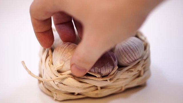 Garlic in a wicker basket, on a white background. Dried French garlic. Red garlic.