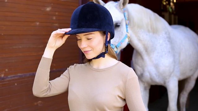 Portrait of a beautiful girl in a helmet on the background of a horse
