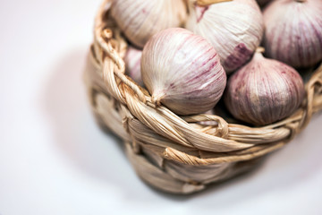 Garlic in a wicker basket, on a white background. Dried French garlic. Red garlic.