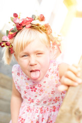 freches Kind mit Blumenkranz auf Spielplatz