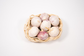Garlic in a wicker basket, on a white background. Dried French garlic. Red garlic.