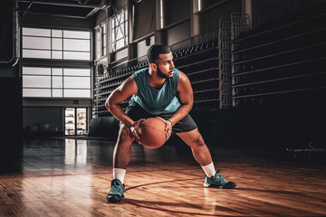 Full body portrait of Black professional basketball player in an action in basketball field.