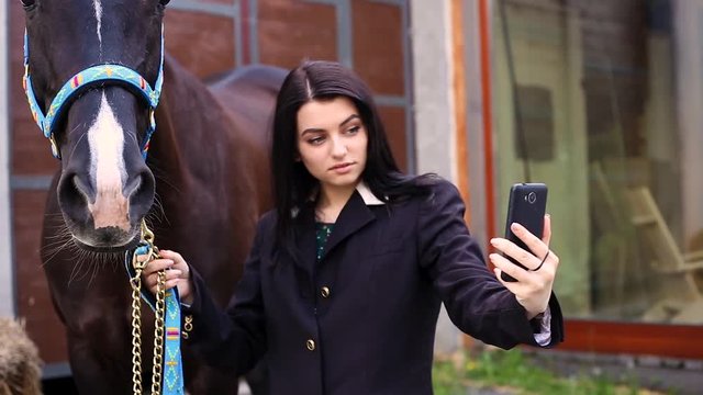 Young beautiful girl makes selfie with a brown horse